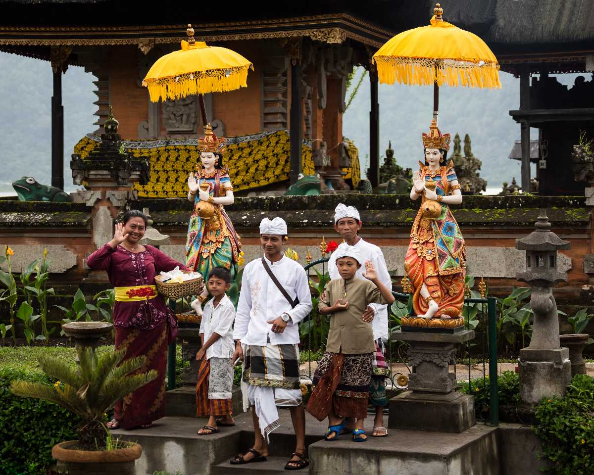 A group of people wearing traditional Balinese clothing pose for a photo in front of a temple.